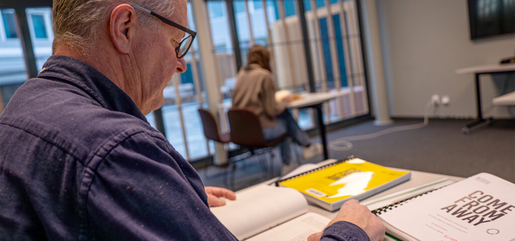 Två personer läser noter, teatermanus och böcker i Musik- och teaterbibliotekets läsesal.